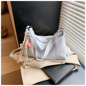 Detail of light blue shoulder bag with pink heart charm and striped rope on a blazer