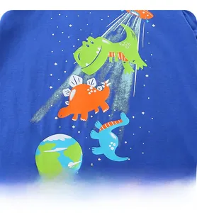 Close-up of cute cartoon dinosaur and UFO print on blue cotton t-shirt for boys