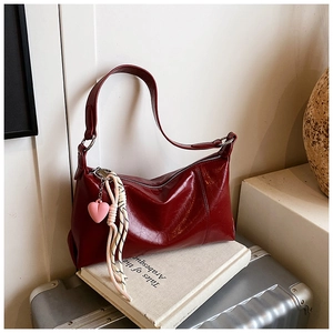 Detail of burgundy hobo bag with vintage texture and heart charm on silver suitcase
