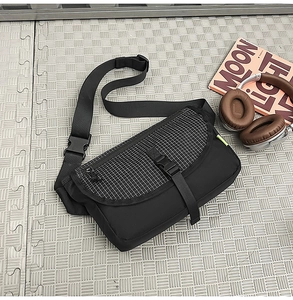 Dettaglio della borsa a tracolla nera con patta a scacchi e chiusura con fibbia in plastica