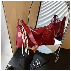 Close-up of red patent leather shoulder bag with a pink heart pendant and silver zipper