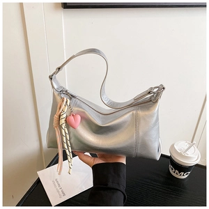 Detail of silver metallic crescent bag featuring pink heart pendant and woven strap