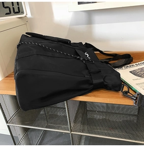 Close-up of black nylon tote bag with side letter print on a wooden desk setting