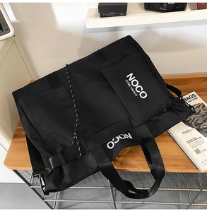 Close-up of black nylon tote bag with white NOCO letter print on a wooden desk