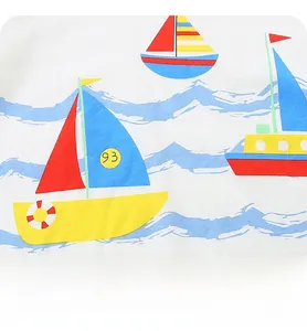 Close-up of printed cartoon sailboats and blue sea waves on a soft cotton kid's T-shirt
