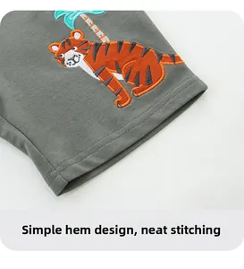 Detail of embroidered tiger and palm tree on gray cotton boys sports shorts with flat seams