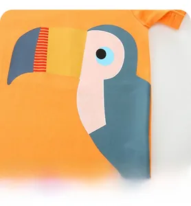 Gros plan d'un t-shirt enfant orange en coton avec un imprimé toucan coloré