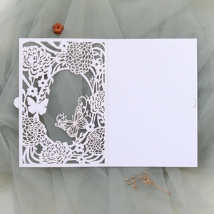 Macro detail of laser-cut white wedding invitation featuring butterfly and floral patterns