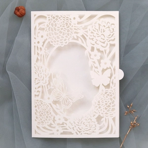 Detail of white laser-cut wedding invitation featuring intricate floral and butterfly patterns
