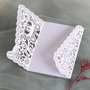 Detailed laser-cut white wedding invitation featuring a carriage and lace design