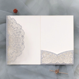 Macro detail of laser-cut hollow lace invitation with silver glitter finish and pocket