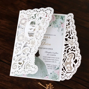 Detail of laser-cut lace invitation featuring intricate carriage patterns and floral inner page