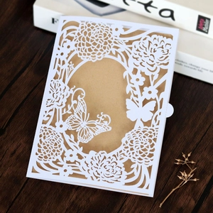 Laser-cut white wedding invitation with floral butterfly patterns and kraft paper insert
