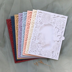 Macro shot of laser-cut floral invitations in multiple colors with butterfly patterns