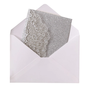 Close-up of silver glitter wedding invitation with laser cut lace and white envelope