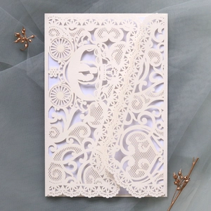 Detailed laser-cut wedding invitation featuring lace texture and pumpkin carriage design