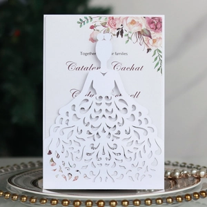 Detail of white laser-cut wedding invitation featuring bridal dress patterns and roses