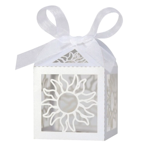 Close-up of white laser-cut hollow sun pattern candy box with satin ribbon bow