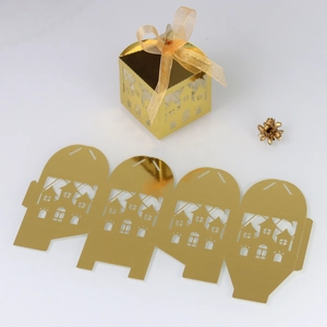 Macro detail of laser-cut golden favor box with house motif and organza ribbon
