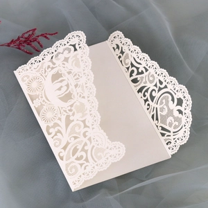 Detail of laser-cut wedding invitation featuring hollow lace and carriage pattern on pearl paper