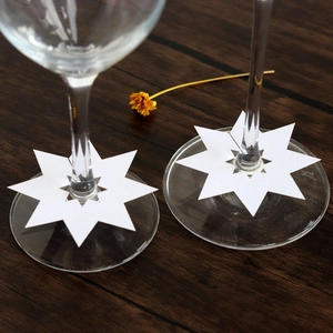 Detail van achthoekige witte parelmoer papieren tafelkaartjes op de steel van wijnglazen