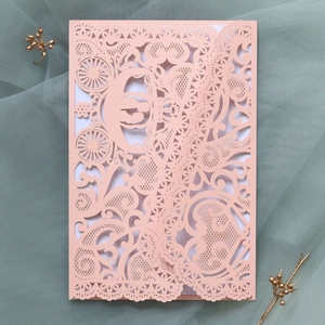 Detail of pink laser-cut wedding invitation featuring intricate carriage lace patterns