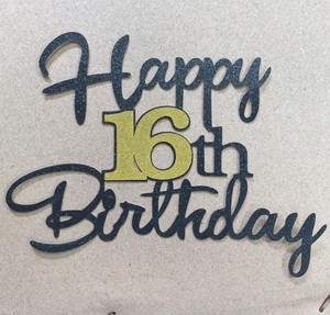 Macro shot of gold glitter Happy 16th Birthday cake topper on black cardstock