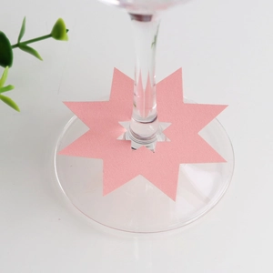 Detailweergave van de roze stervormige tafelkaart aan de wijnglassteel voor feestdecor