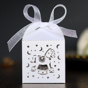 Macro shot of white laser-cut rocking horse favor box with star and moon patterns