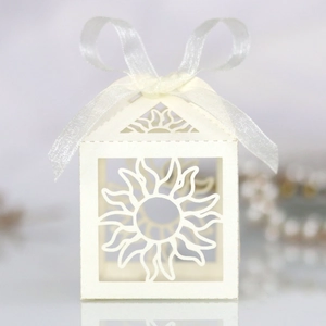 Detail of white laser-cut hollow paper gift box with sun patterns and organza ribbon bow