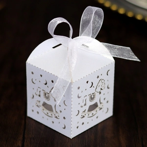 Detail of white laser-cut favor box with rocking horse and star patterns