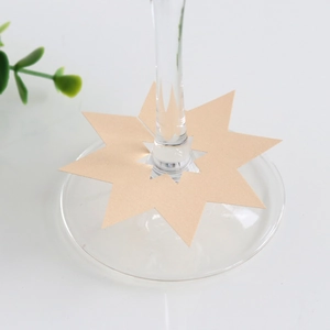 Detail van stervormig kraftpapier plaatskaartje aan de steel van een wijnglas