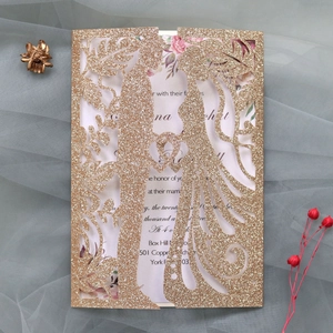 Λεπτομερής λήψη χρυσής πρόσκλησης γάμου laser-cut με ρομαντική σιλουέτα ζευγαριού σε καρδιά