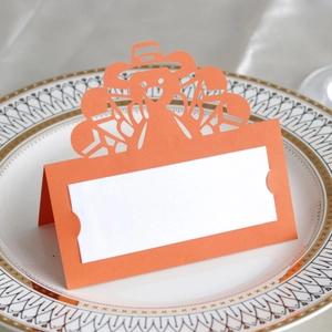 Detail of laser-cut turkey place card on white plate for Thanksgiving table setting