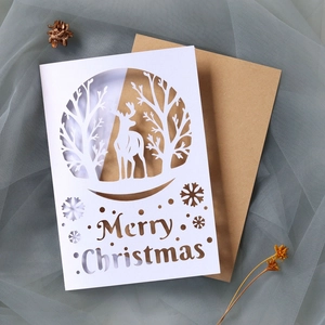 Close-up of laser-cut reindeer and Merry Christmas hollow design on white card with envelope
