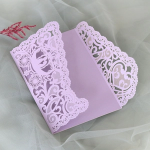 Close-up of laser-cut wedding invitation featuring lavender lace and carriage patterns
