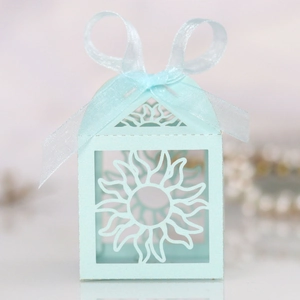 Detail of light blue laser-cut candy box with hollow sun pattern and organza ribbon bow
