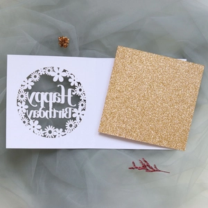 Detail of laser-cut daisy greeting card with gold glitter insert and Happy Birthday text