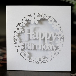 Macro detail of laser-cut white pearl paper Happy Birthday card with daisy patterns
