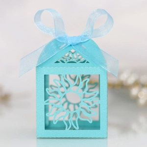 Macro detail of laser-cut sunflower pattern on light blue paper wedding candy gift box