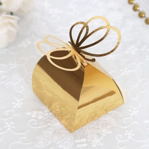 Close-up of golden metallic candy box with laser-cut butterfly on white lace background