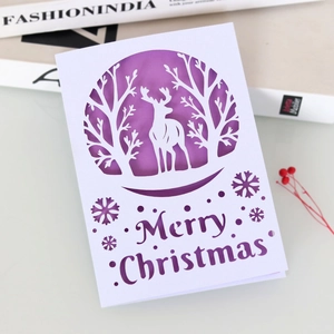 Laser-cut Christmas card with white elk forest design over a purple background