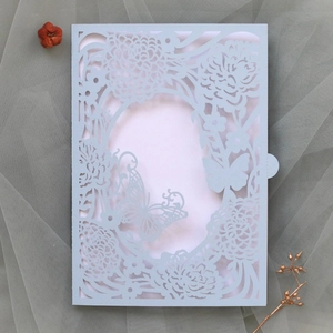 Macro detail of laser-cut butterfly and floral patterns on light blue wedding invitation