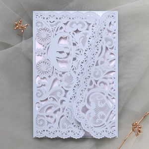 Intricate laser-cut wedding invitation detail with elegant lace pattern and carriage design