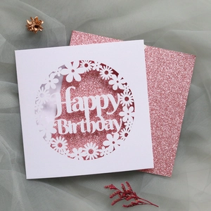 Detail of laser-cut daisy hollow pattern and pink glitter insert on Happy Birthday card