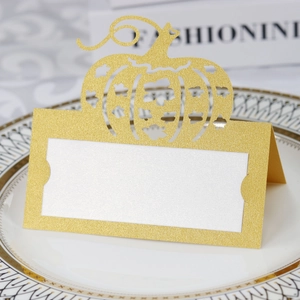 Detail of laser-cut gold glitter pumpkin place card on elegant white china dinnerware