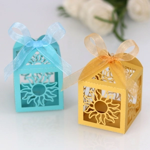 Detailed view of laser-cut sun patterns on blue and gold favor boxes with ribbons
