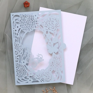 Detail of laser cut flower and butterfly patterns on light blue wedding invitation card