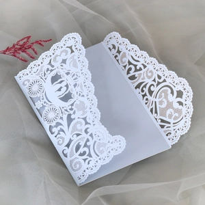 Detailed macro of laser-cut hollow lace wedding invitation with romantic carriage design
