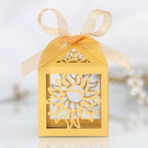 Detail of laser-cut sun pattern on golden paper candy box with yellow ribbon bow